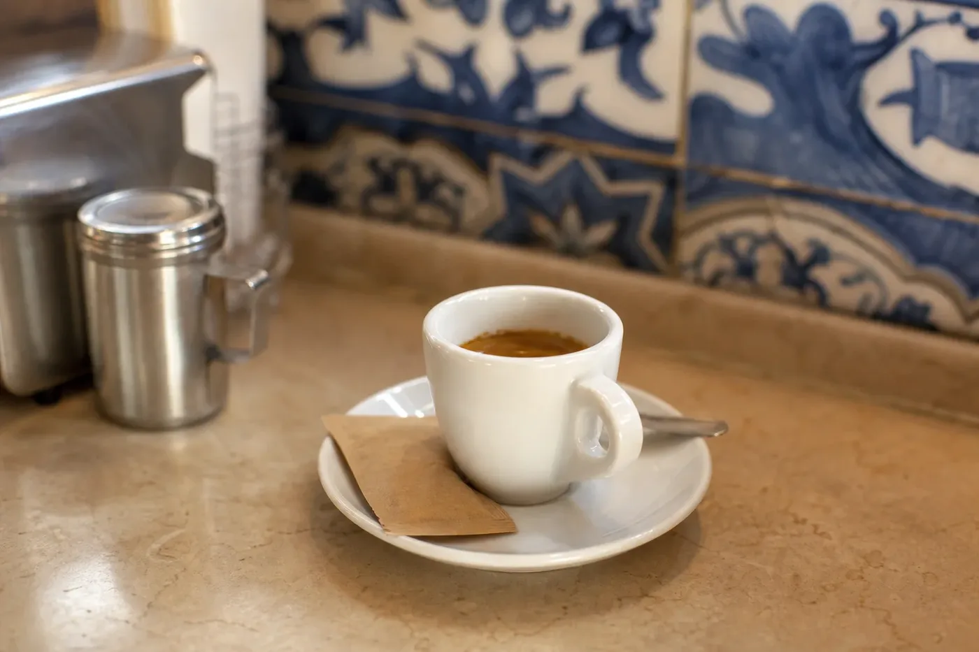 A bica espresso on the counter of a Lisbon cafe with blue tiles behind