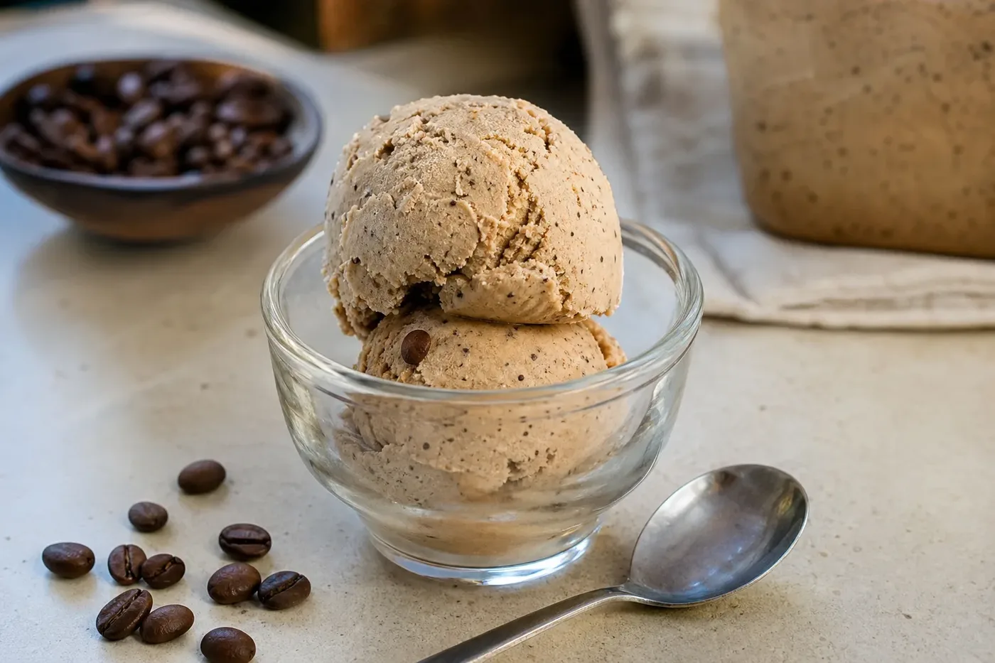Two scoops of coffee ice cream in a glass bowl with coffee beans