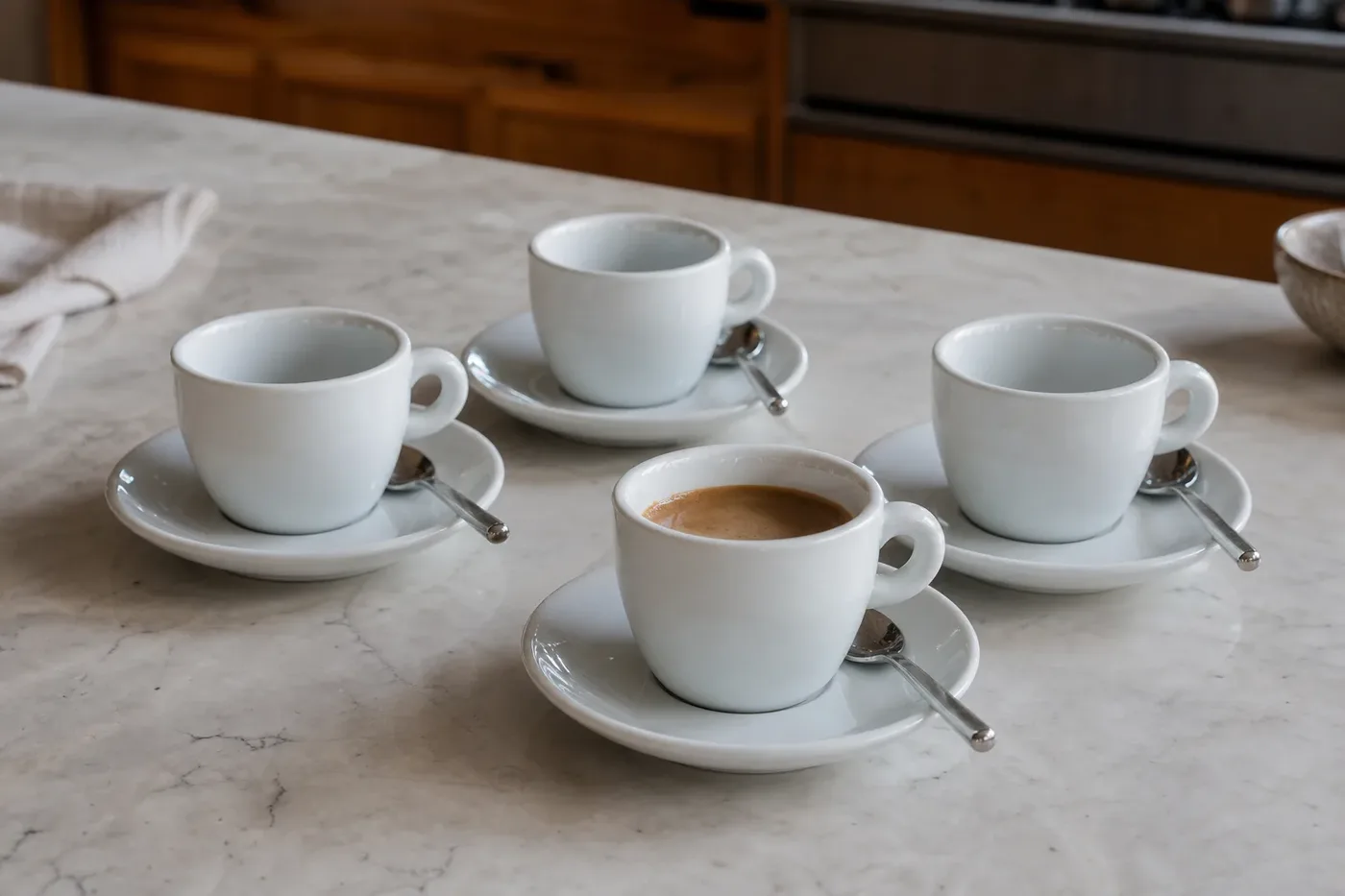 A set of white porcelain demitasse cups with saucers and small spoons