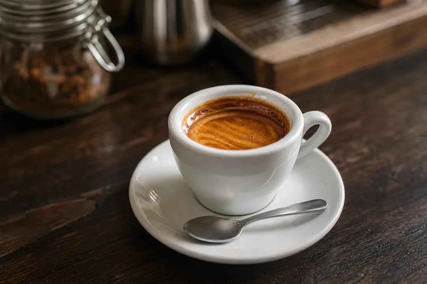 A single espresso with thick hazel crema in a white demitasse cup