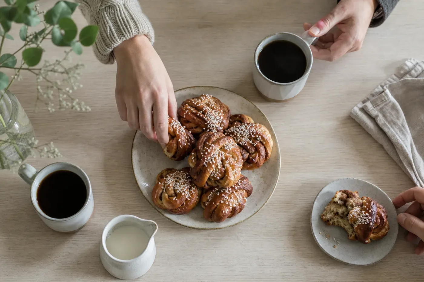 Two mugs of filter coffee and cinnamon buns on a table for Swedish fika