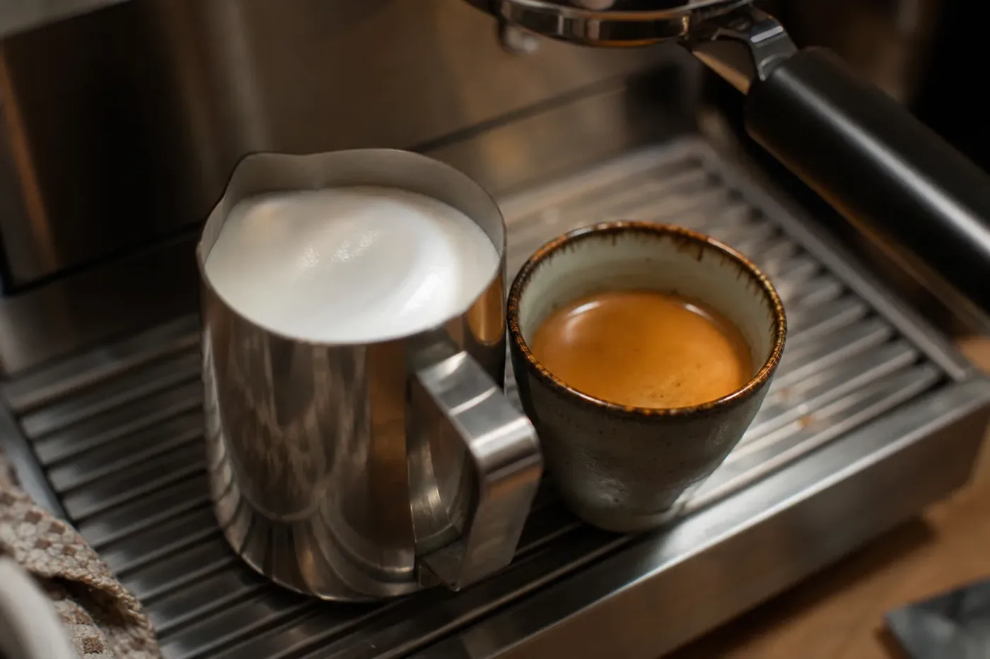 Silky steamed milk ready to pour into a double espresso for a flat white