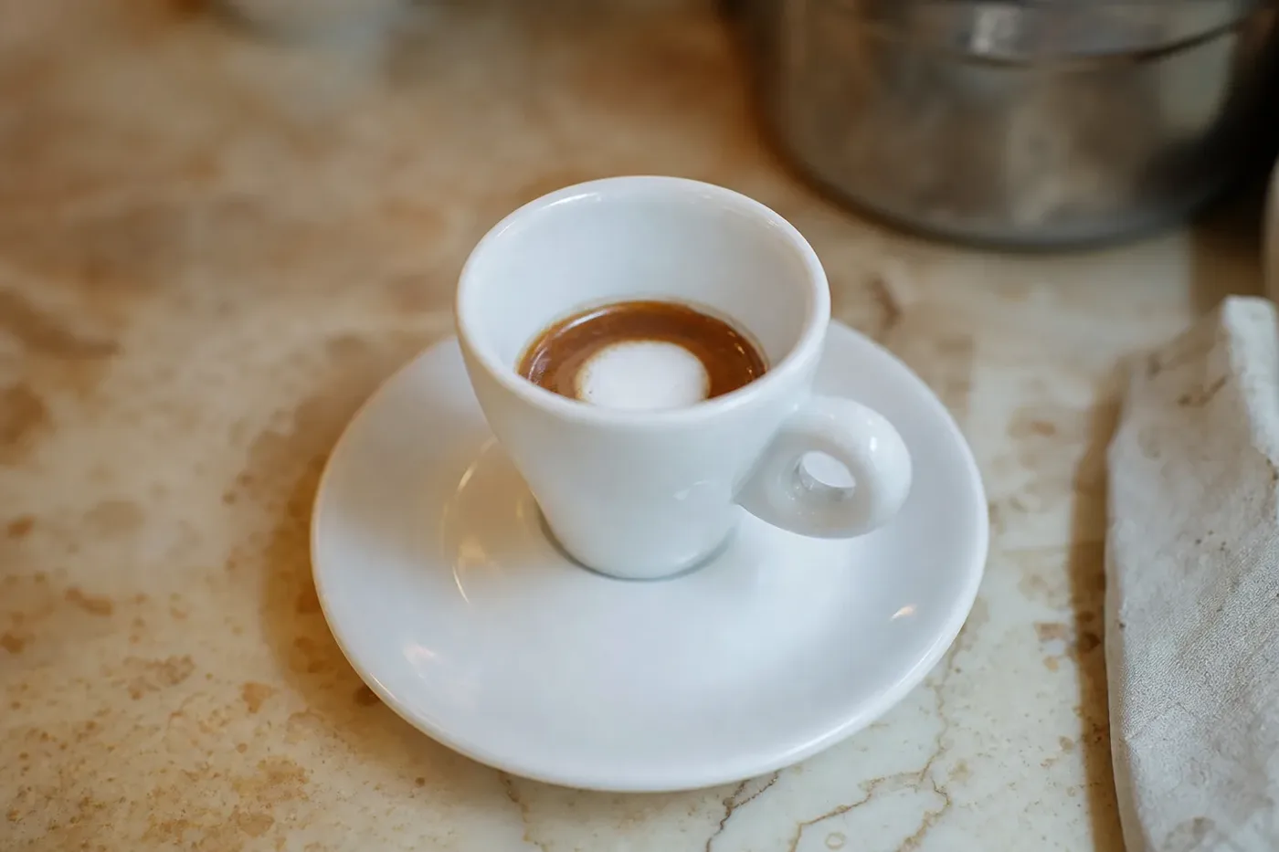 Espresso macchiato in a small cup with a spoonful of milk foam on top