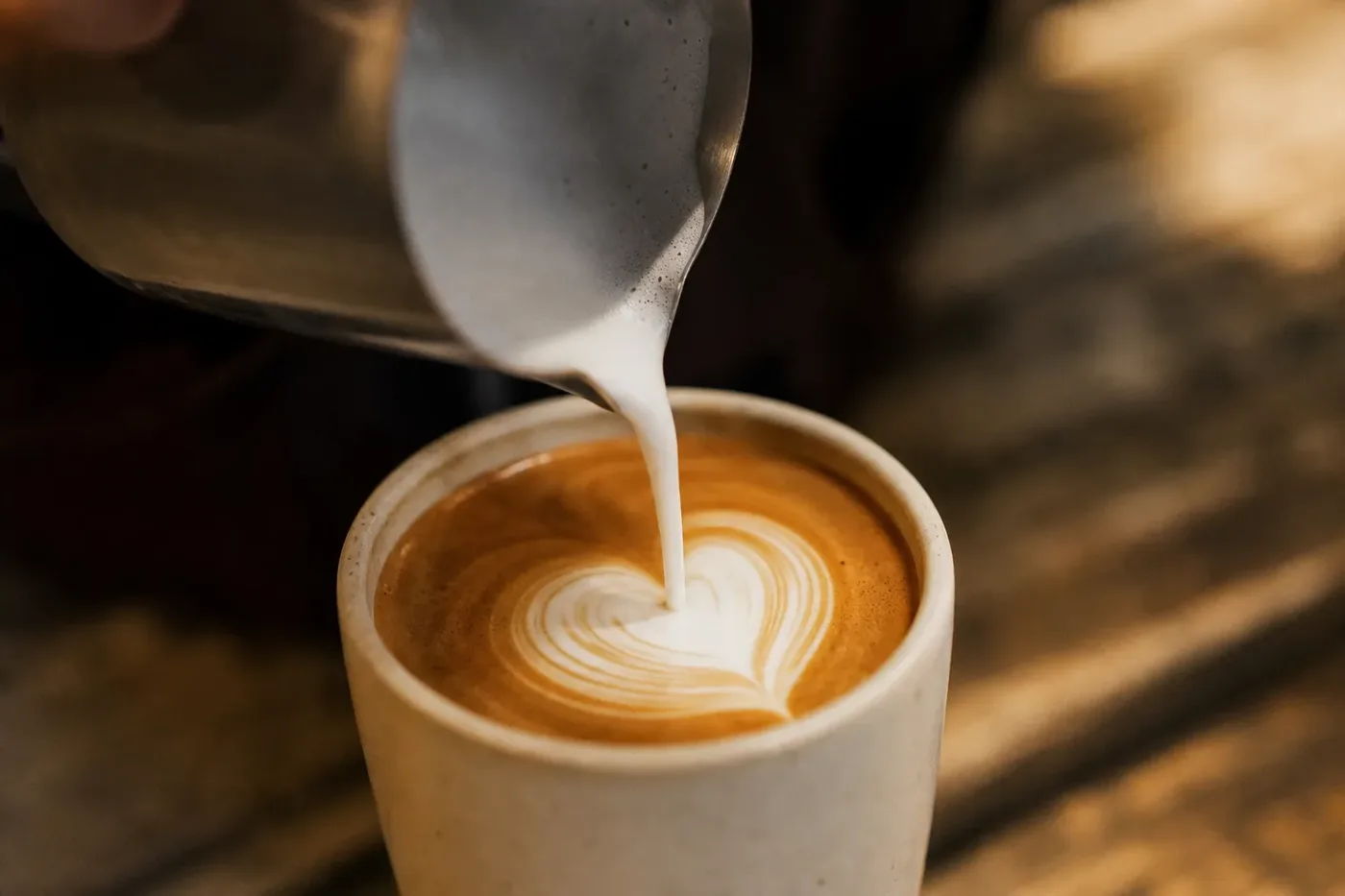 Steamed oat milk poured into espresso making a latte art heart