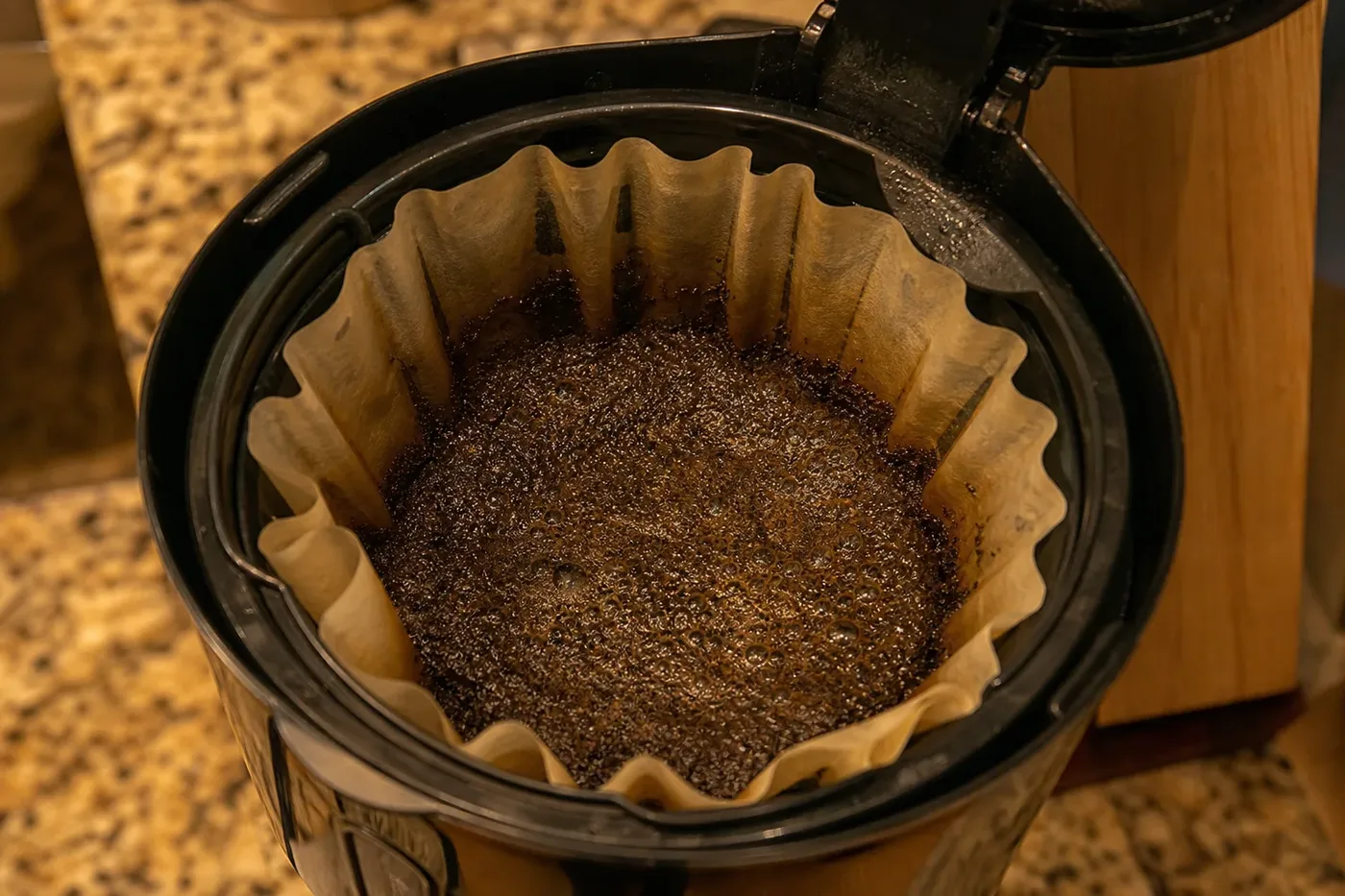 Wet coffee grounds in the paper filter of a drip coffee maker's basket