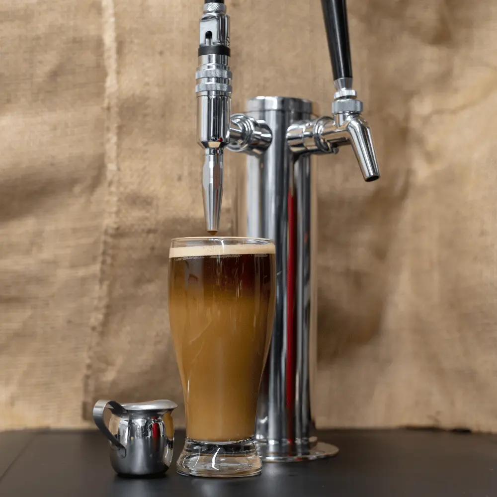 a glass of nitro cold brew coffee in a nitro tower dispenser