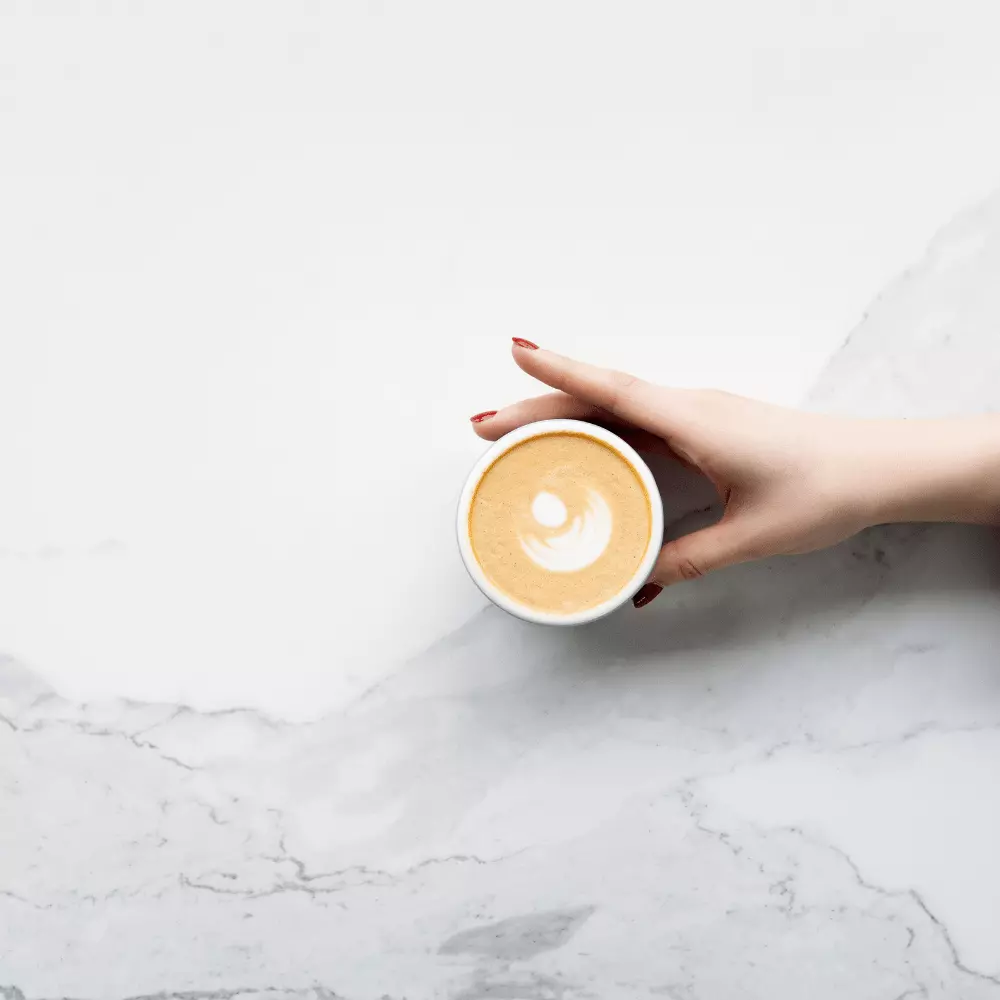 a person holding a cup of coffee on a table