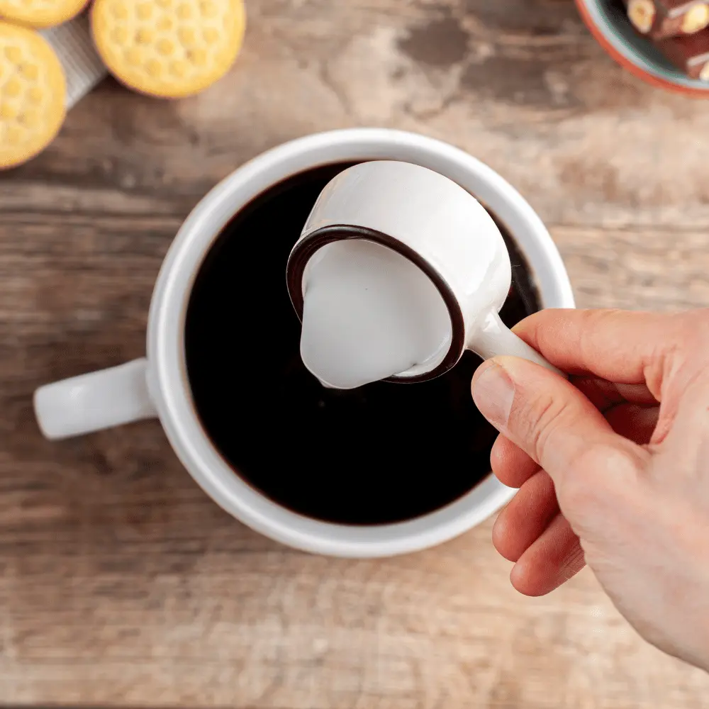 Adding coffee creamer to a cup of black coffee