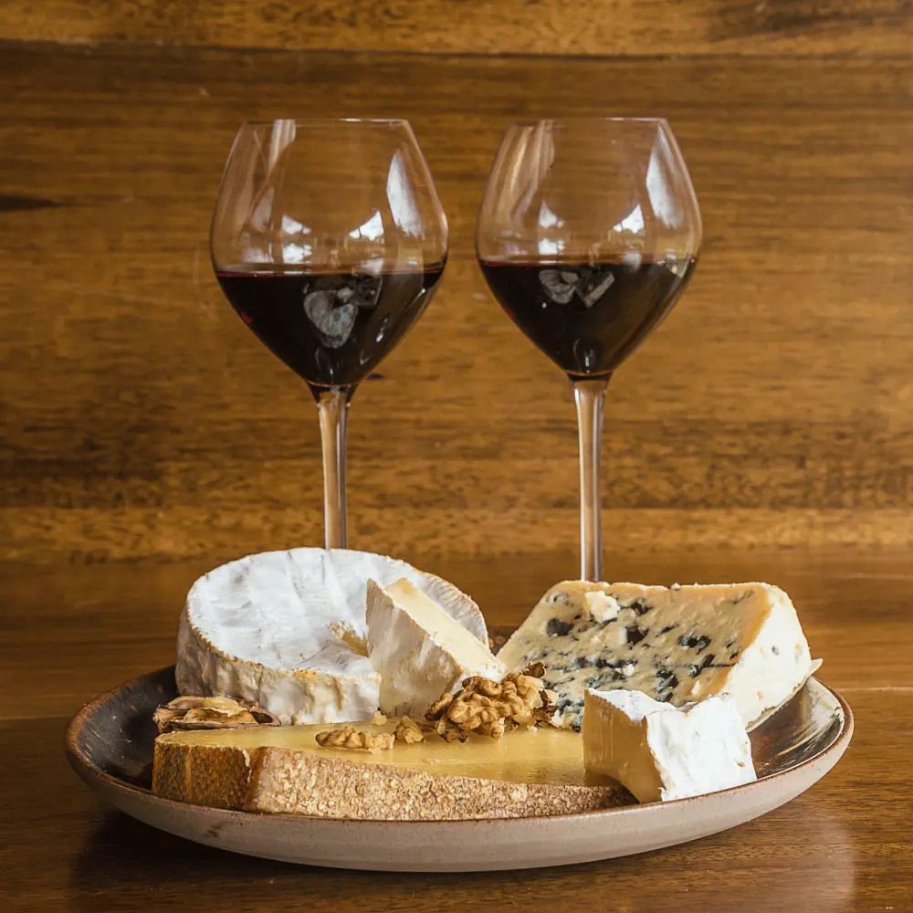 a platter of cheeses served with wine