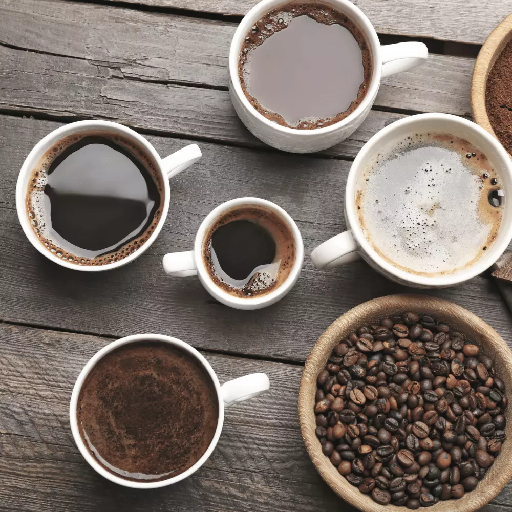 a flight of black coffee drinks with roasted coffee beans on a table