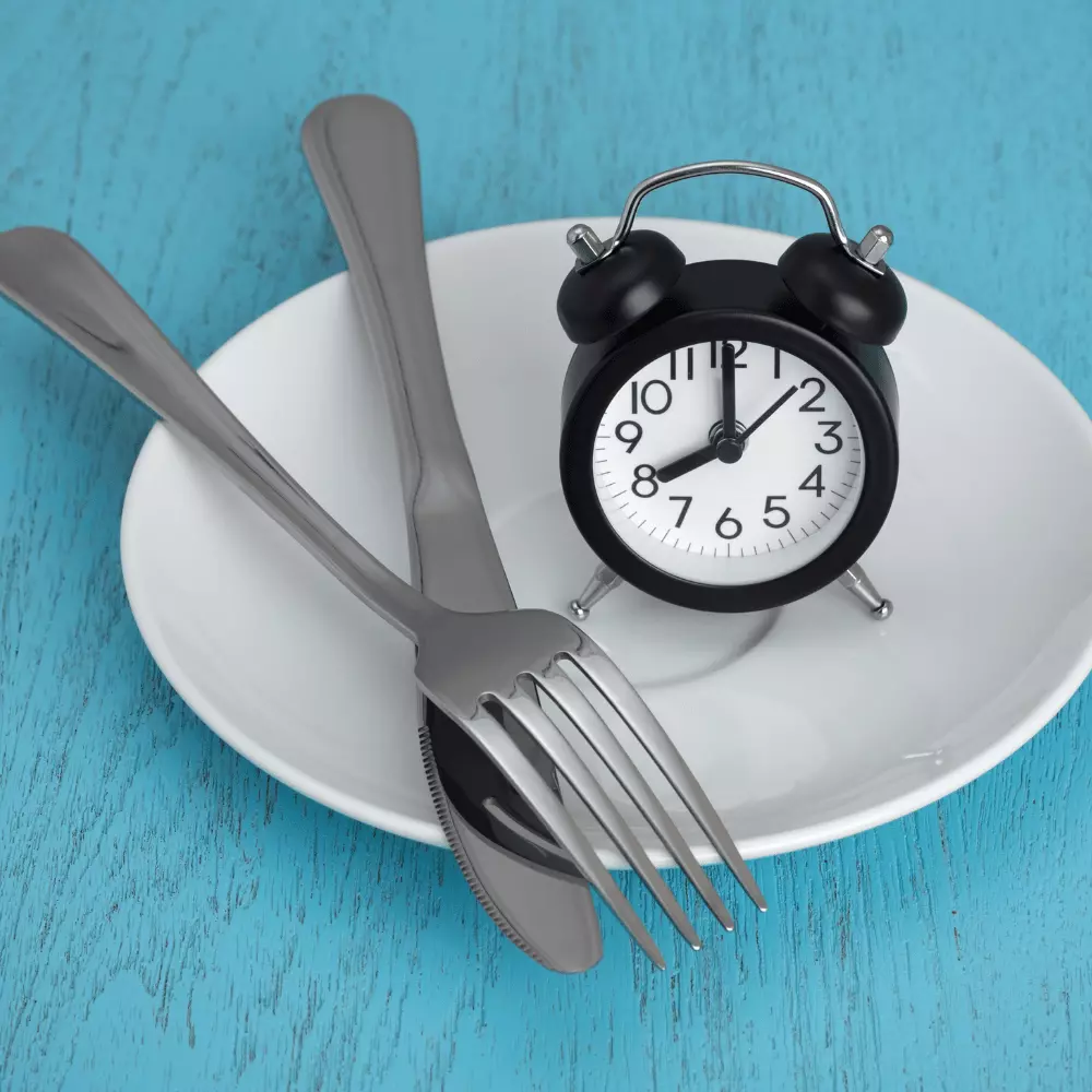 a clock on a white plate with spoon and fork