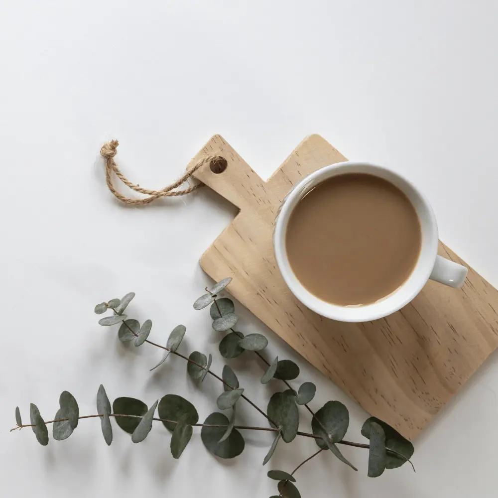 cup of maca coffee with chopping board and leaves on a table