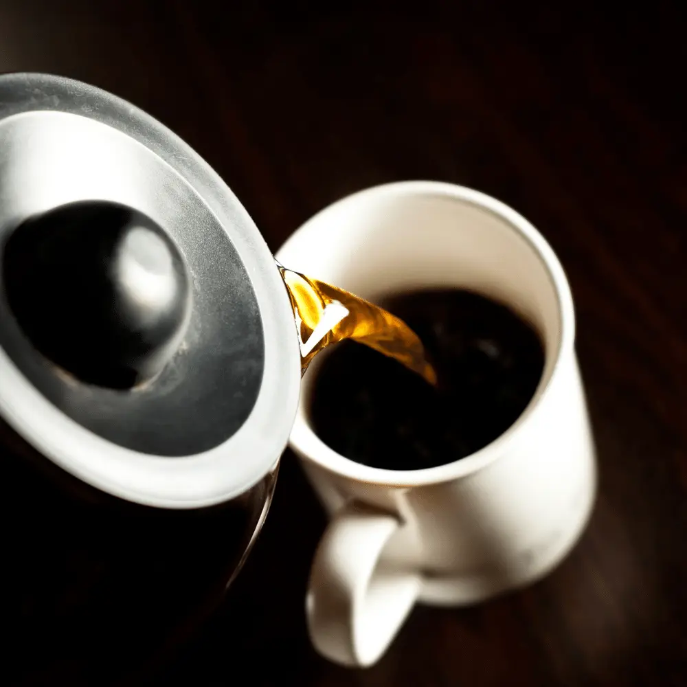 drip coffee being poured into a white coffee mug