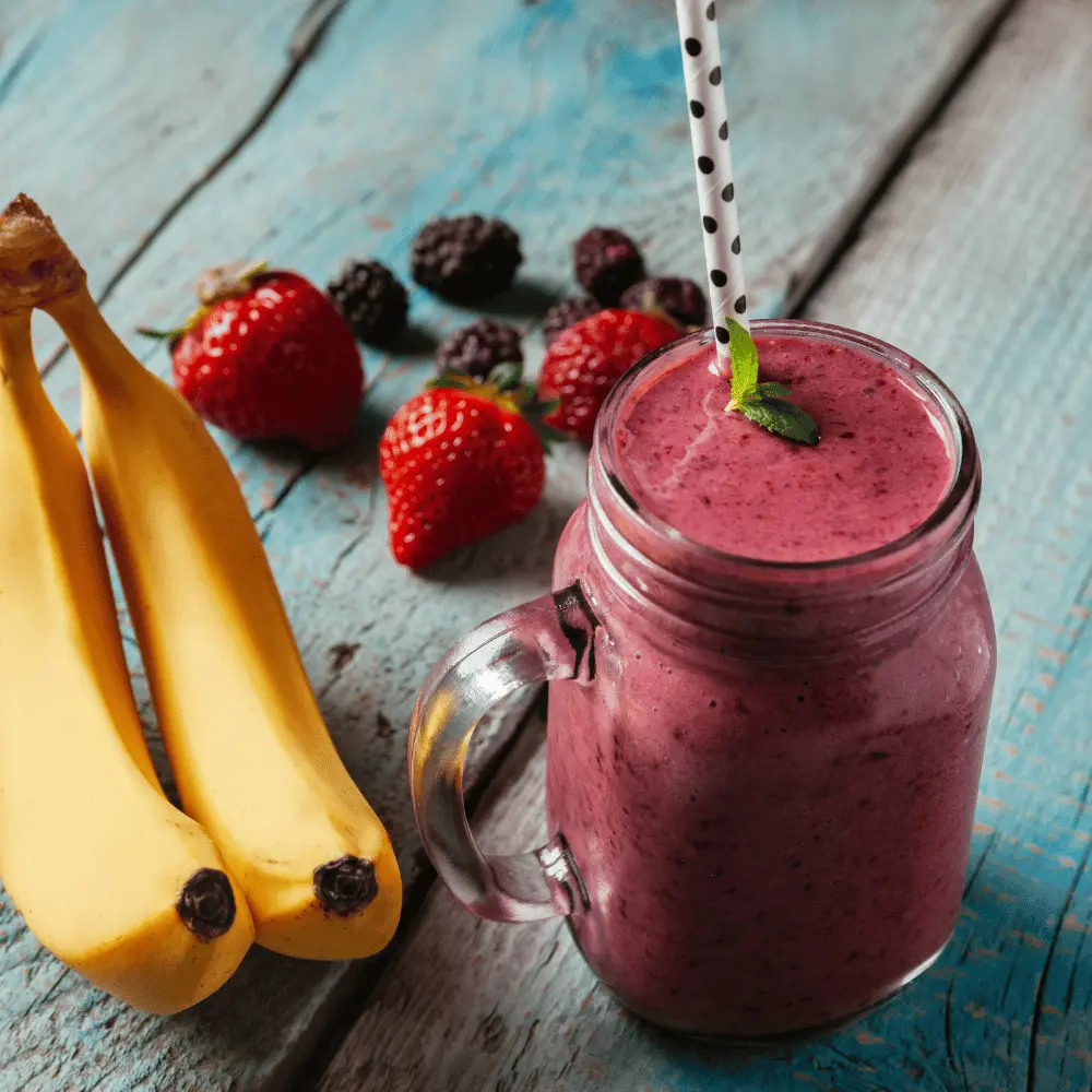 a smoothie on a wooden table with fruit