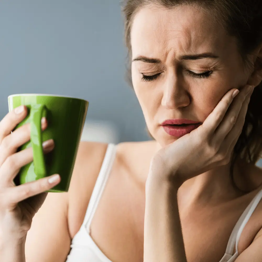 woman experiencing tooth pain while drinking coffee