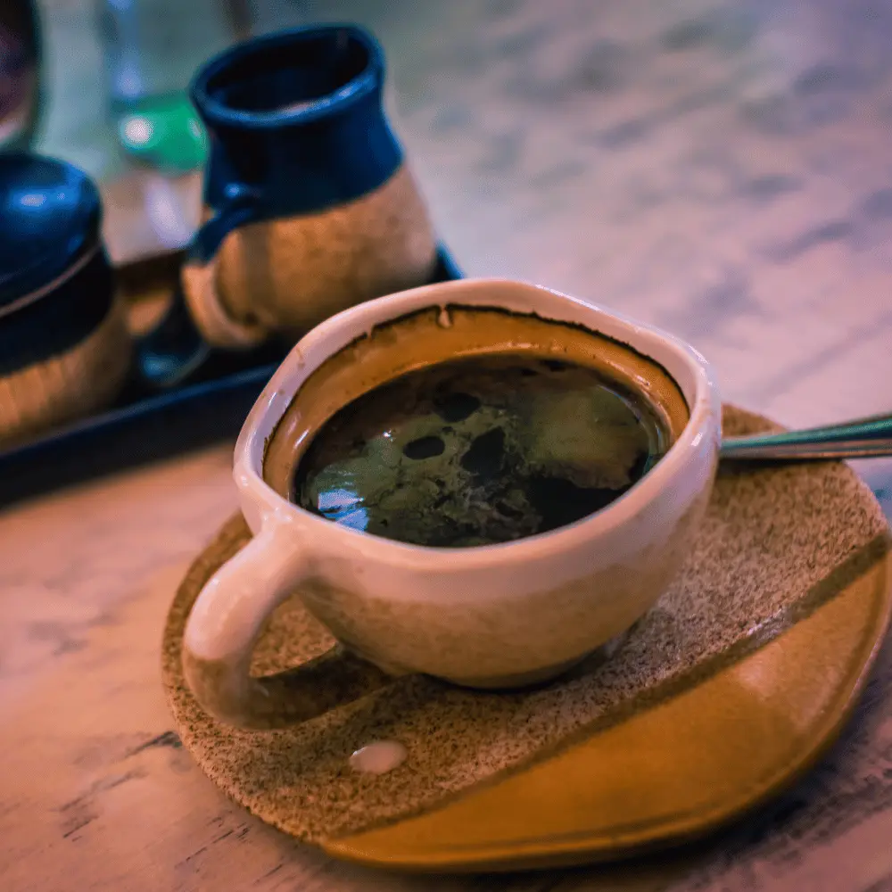 a cup of coffee on a plate with a spoon