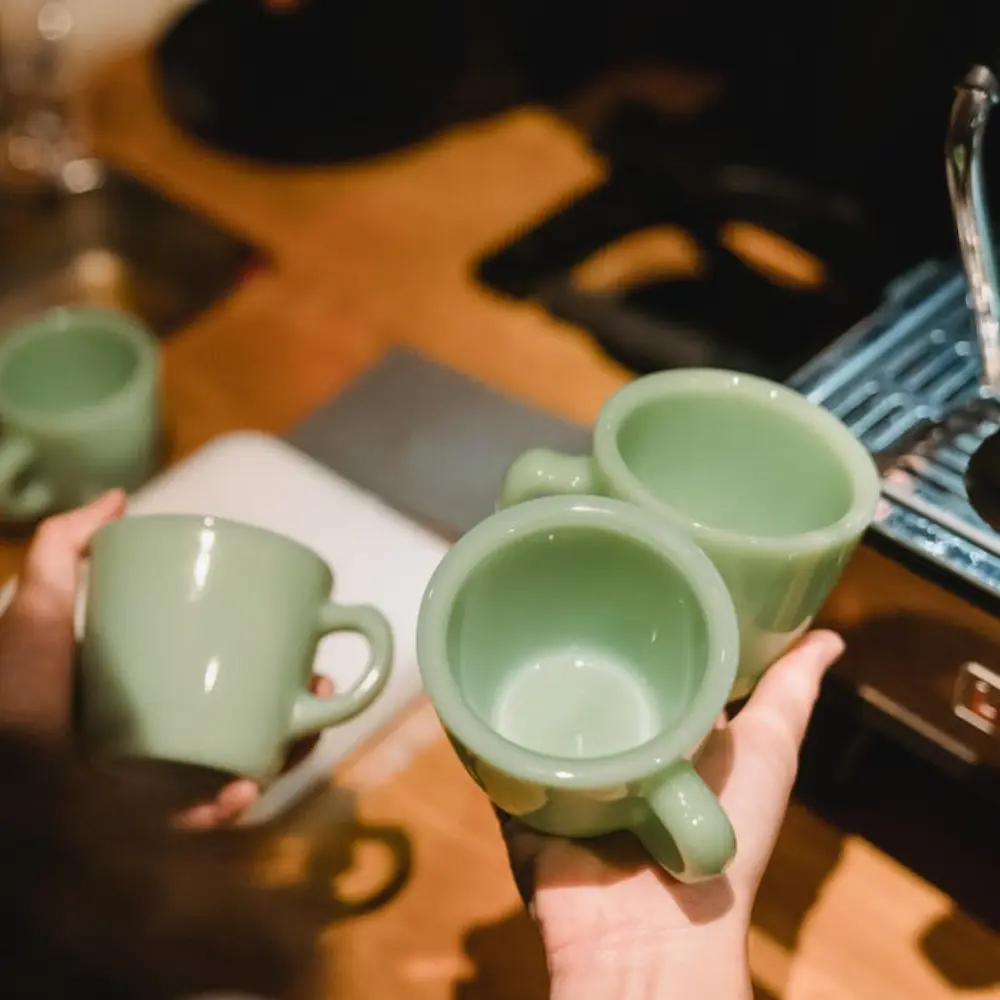 person holding green demitasse cups