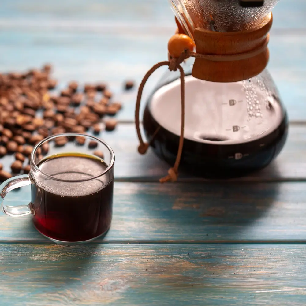 a pour-over brewer with a glass of coffee and beans