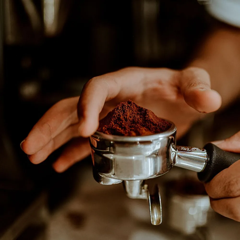 man tamping coffee grinds in a porta filter