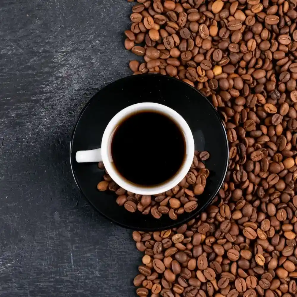 a coffee mug in the middle with black coffee and coffee beans
