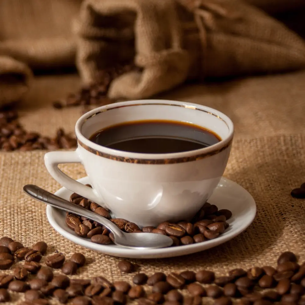 a vintage coffee cup on a saucer with black coffee and beans