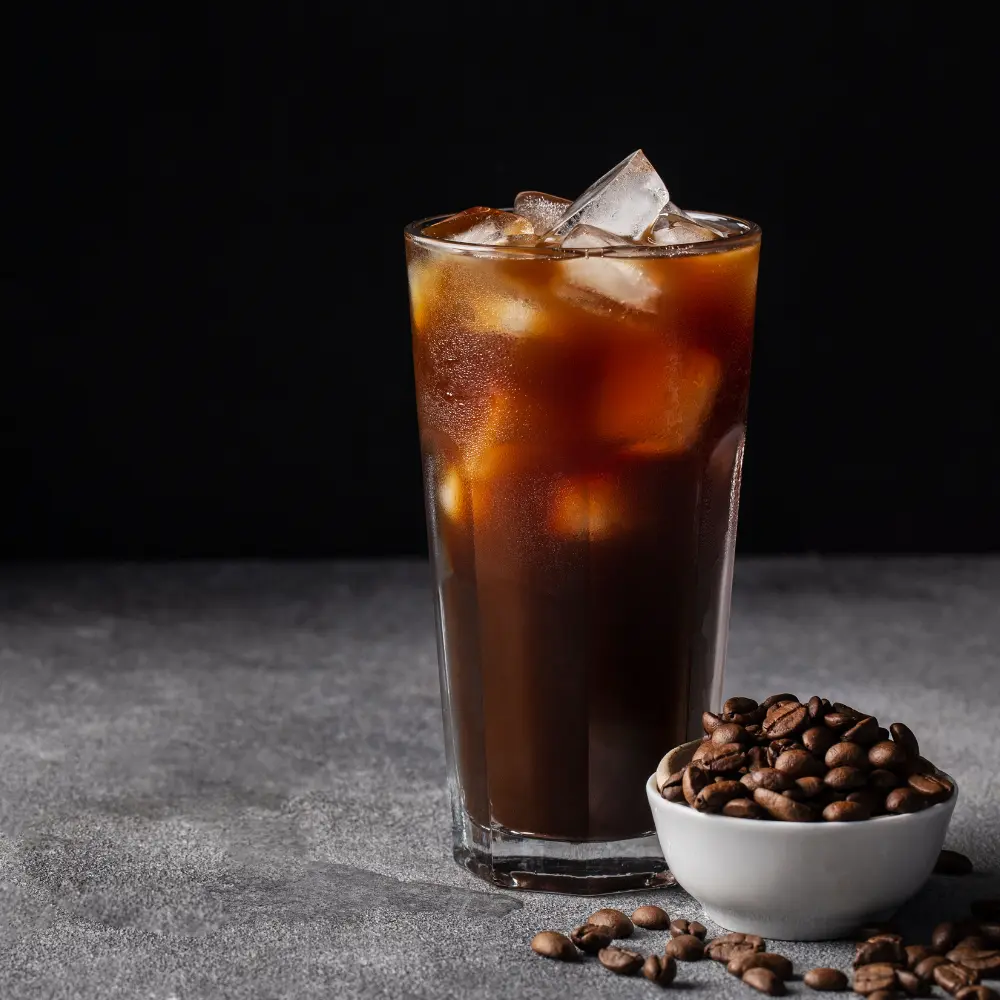 iced coffee with a small bowl of freshly roasted coffee beans