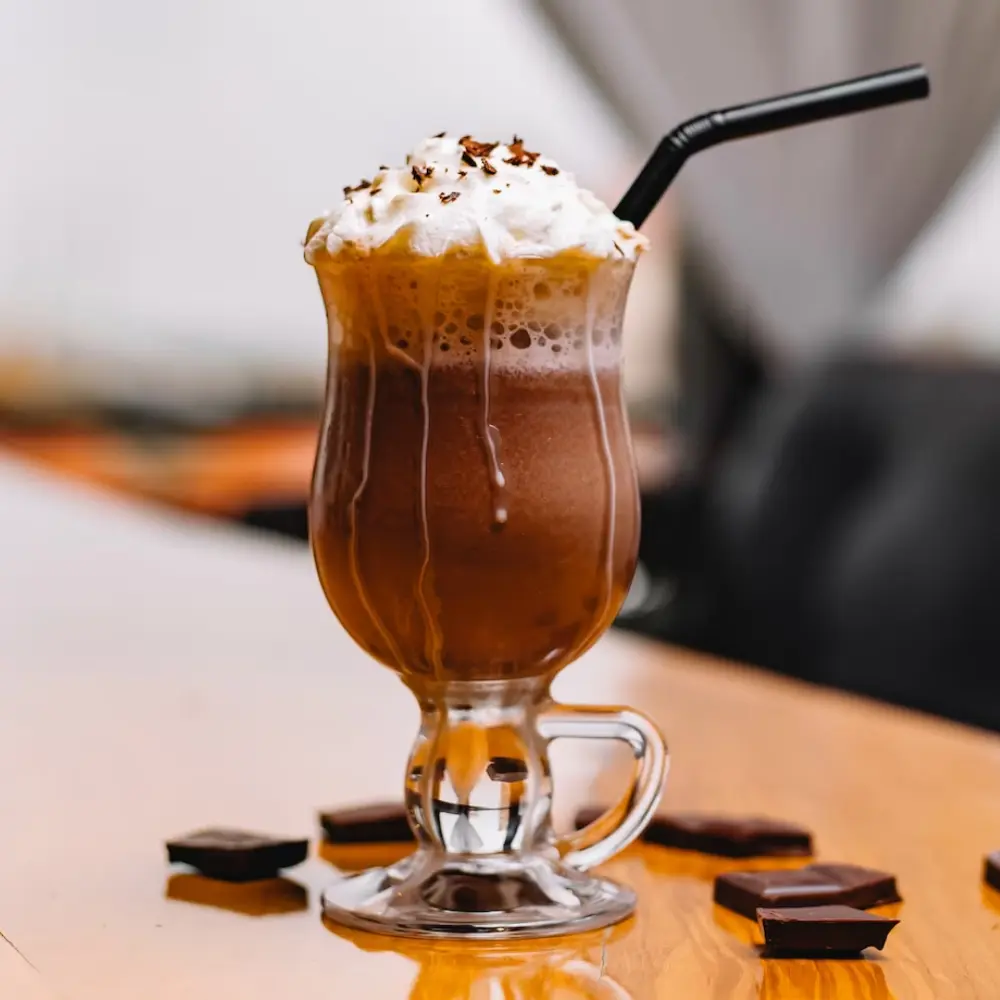 mocha coffee with a lot of cream and a straw in a tall glass