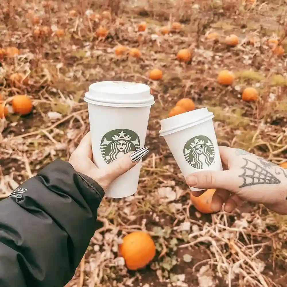 two people holding their starbucks during fall season
