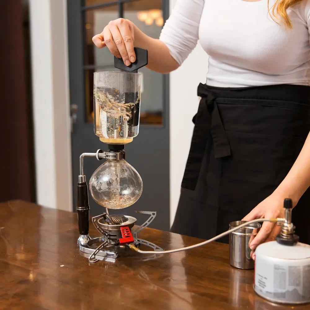woman using siphon coffee maker