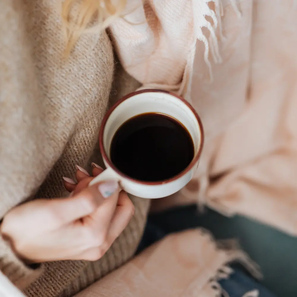 woman holding a cup of black coffee