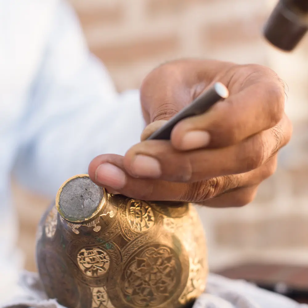 man engraving a dallah coffee pot