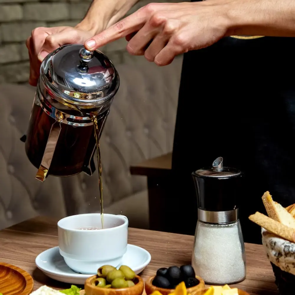 woman pouring freshly brewed coffee from a french press