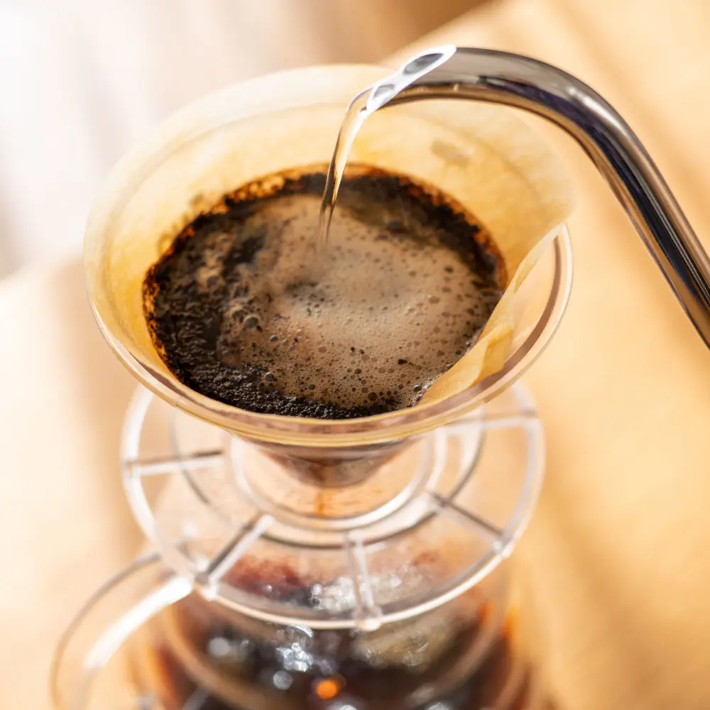 gooseneck kettle pouring water over coffee