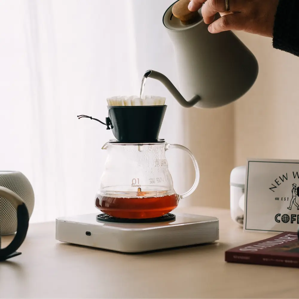 man brewing pour over coffee with a gooseneck kettle