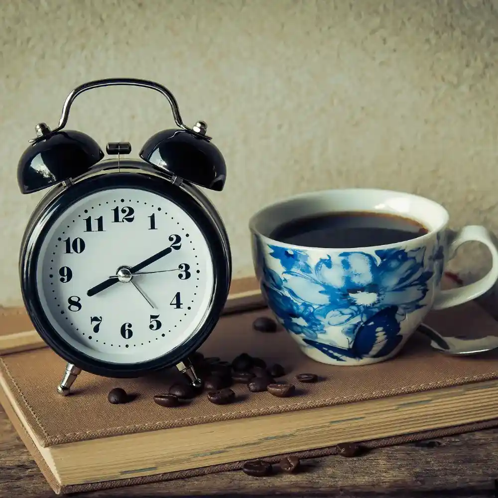an alarm clock next to a cup of coffee