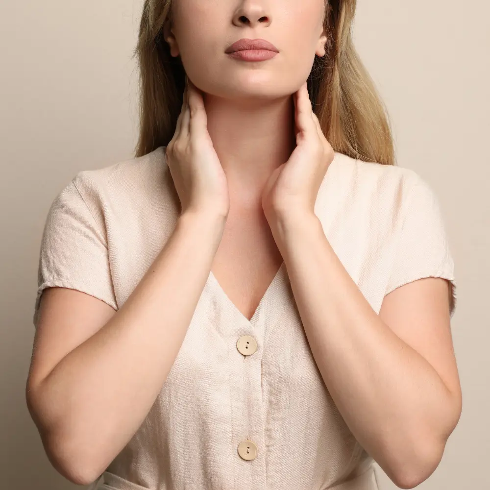 a woman pressing on her neck and checking her thyroid