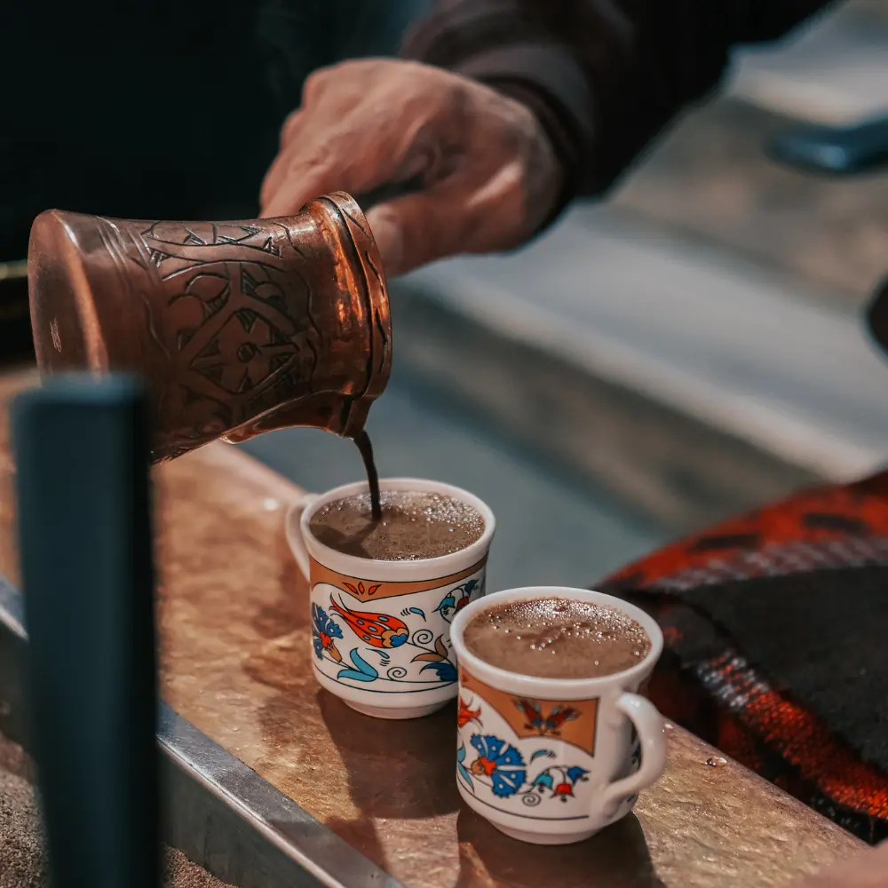 pouring turkish coffee into 2 stunning demitasse cups