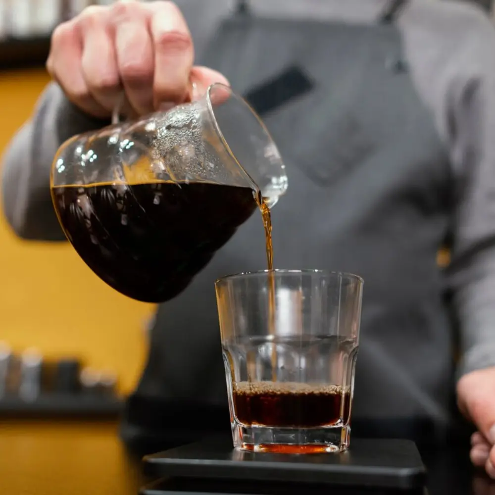 man pouring freshly brewed pour over coffee into a glass
