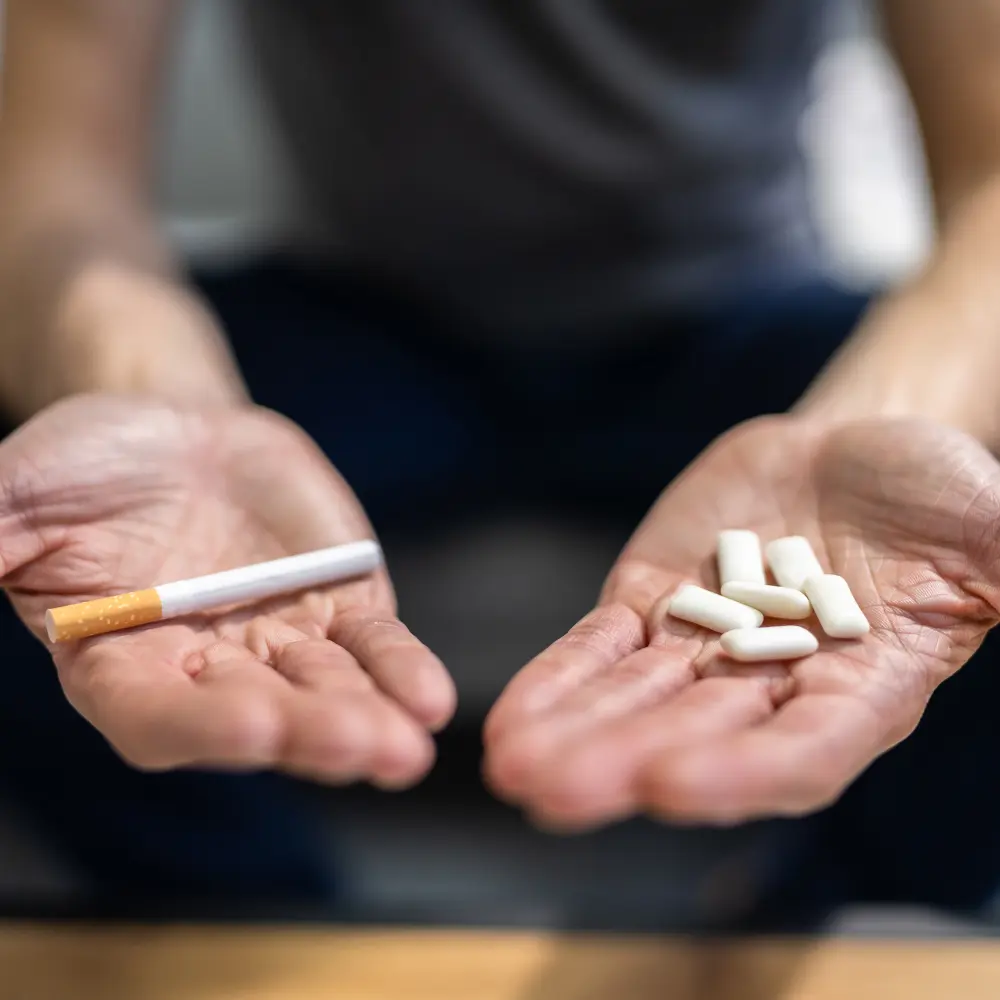 man holding a cigarette and some nicotine gum