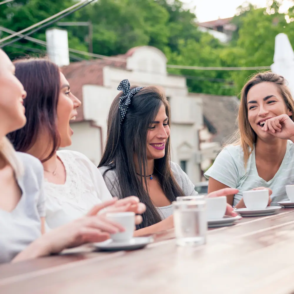 a group of girls laughing and having fun while drinking coffee and smoking