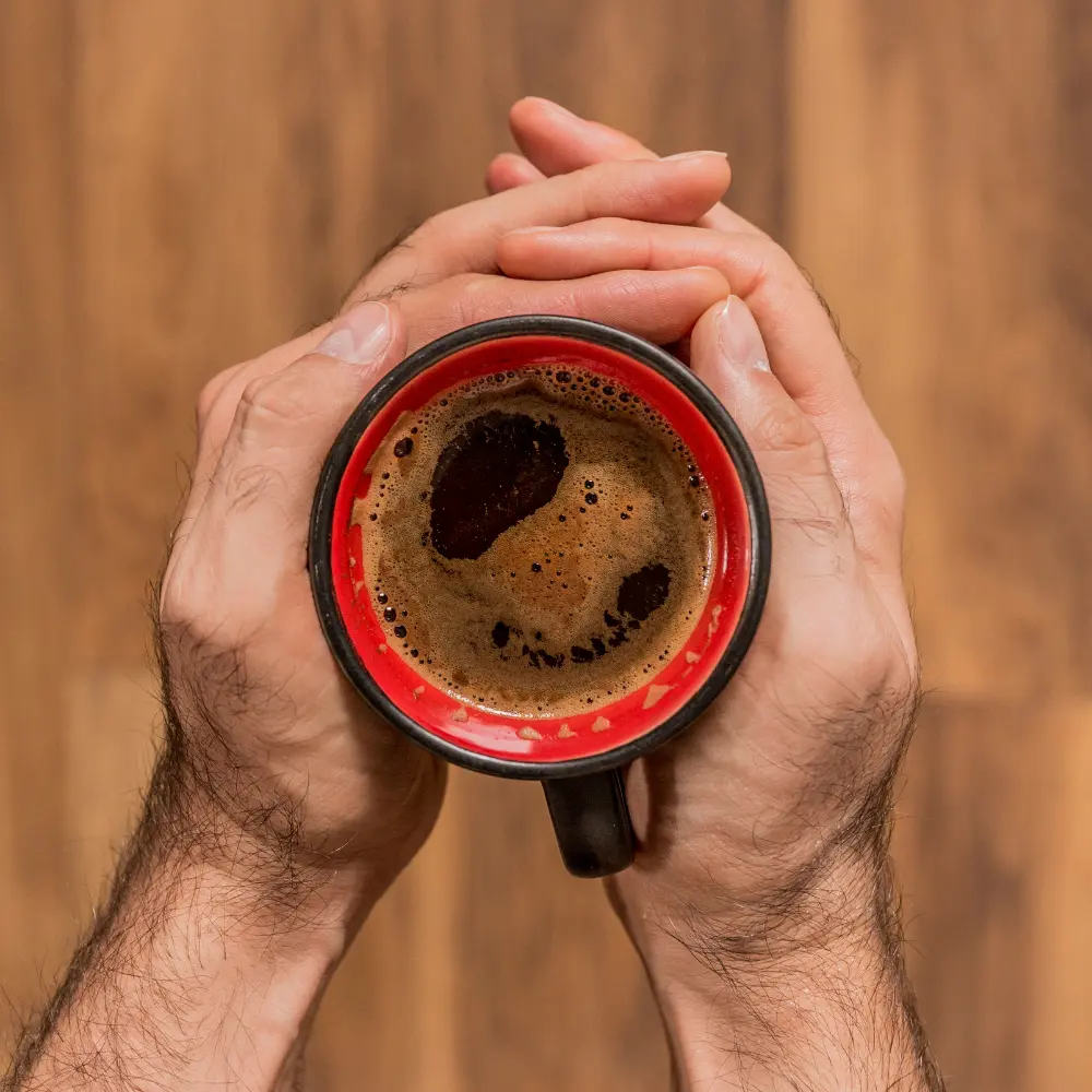 hands holding a cup of black coffee