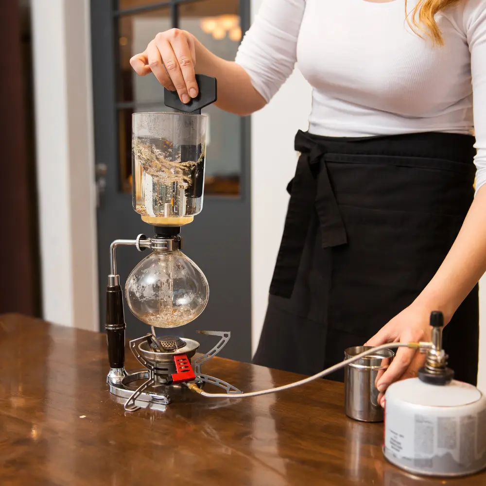 woman using a siphon coffee maker
