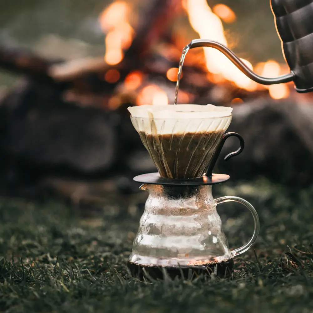 pour over coffee being brewed outdoors near a fire