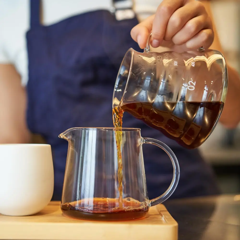pouring coffee from one glass container to another