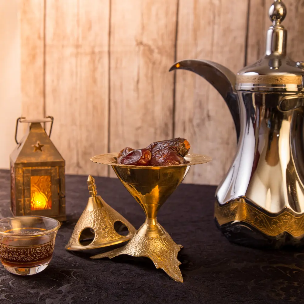 dates in a gold bowl next to a dallah coffee pot