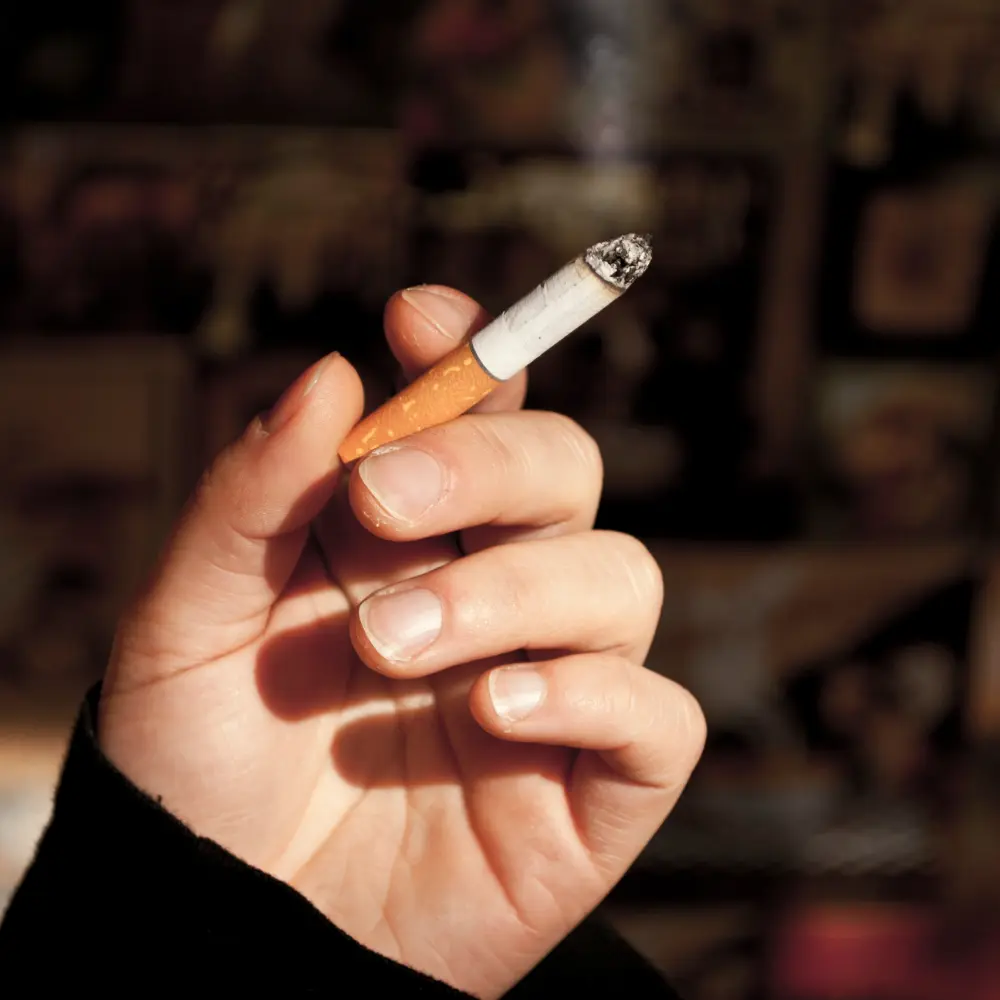 man holding a cigarette while it's burning