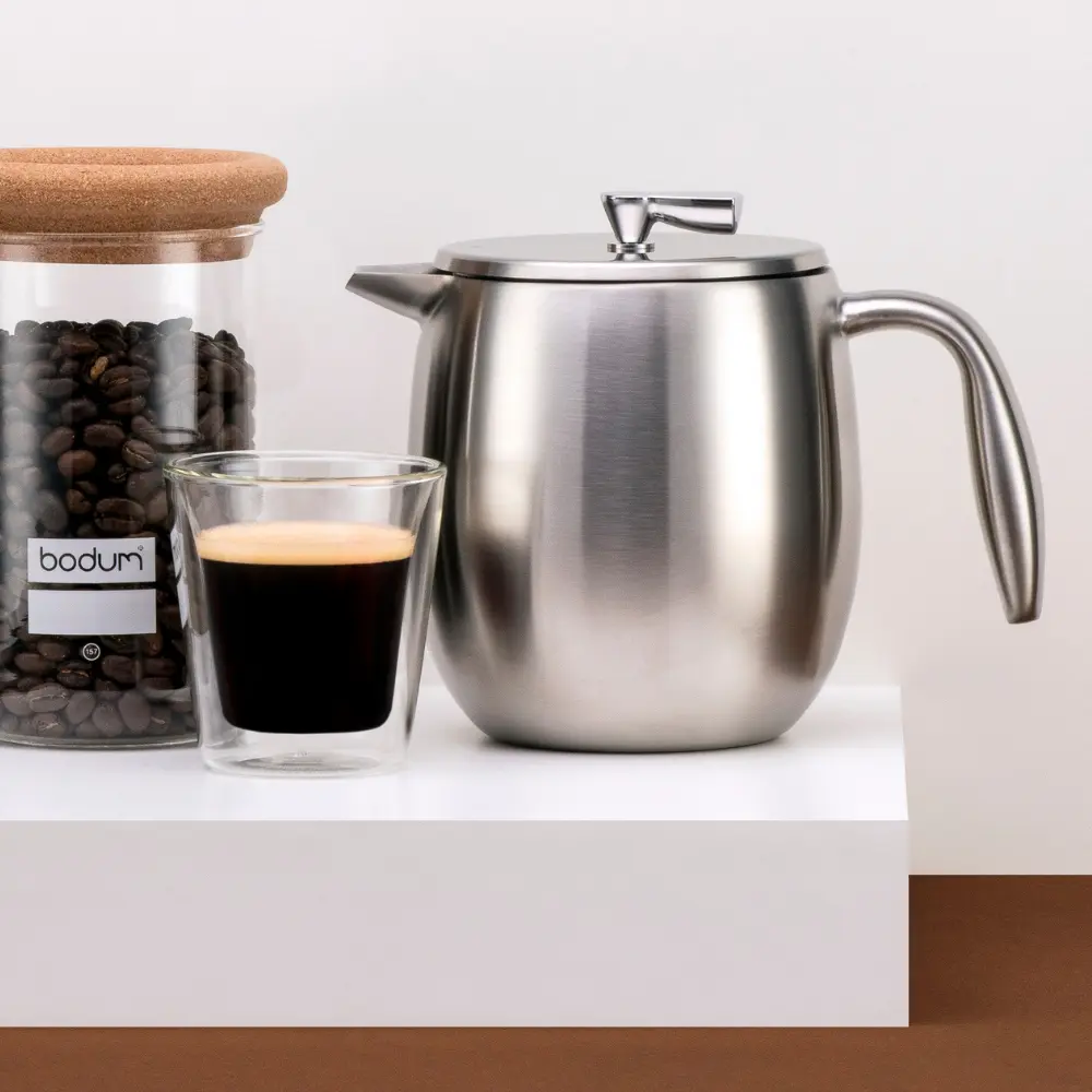 a shiny press next to an americano coffee