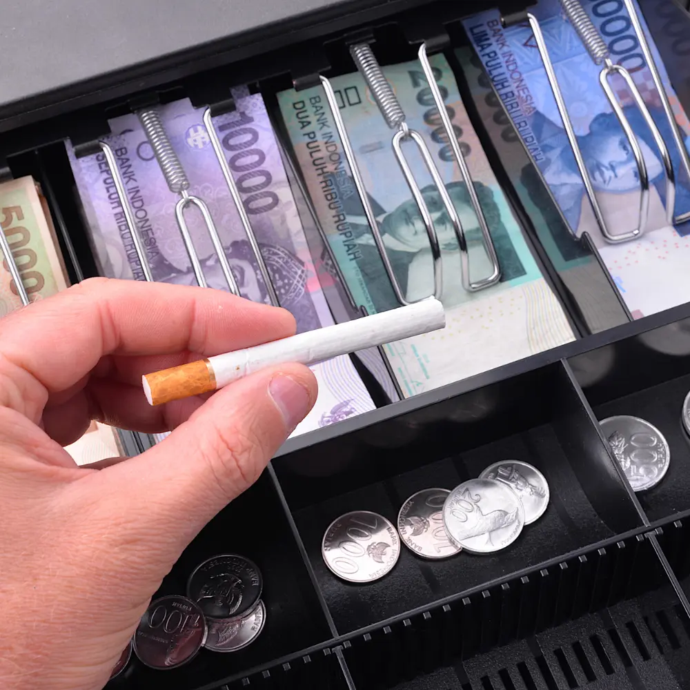 man holding a cigarette in front of a cashier