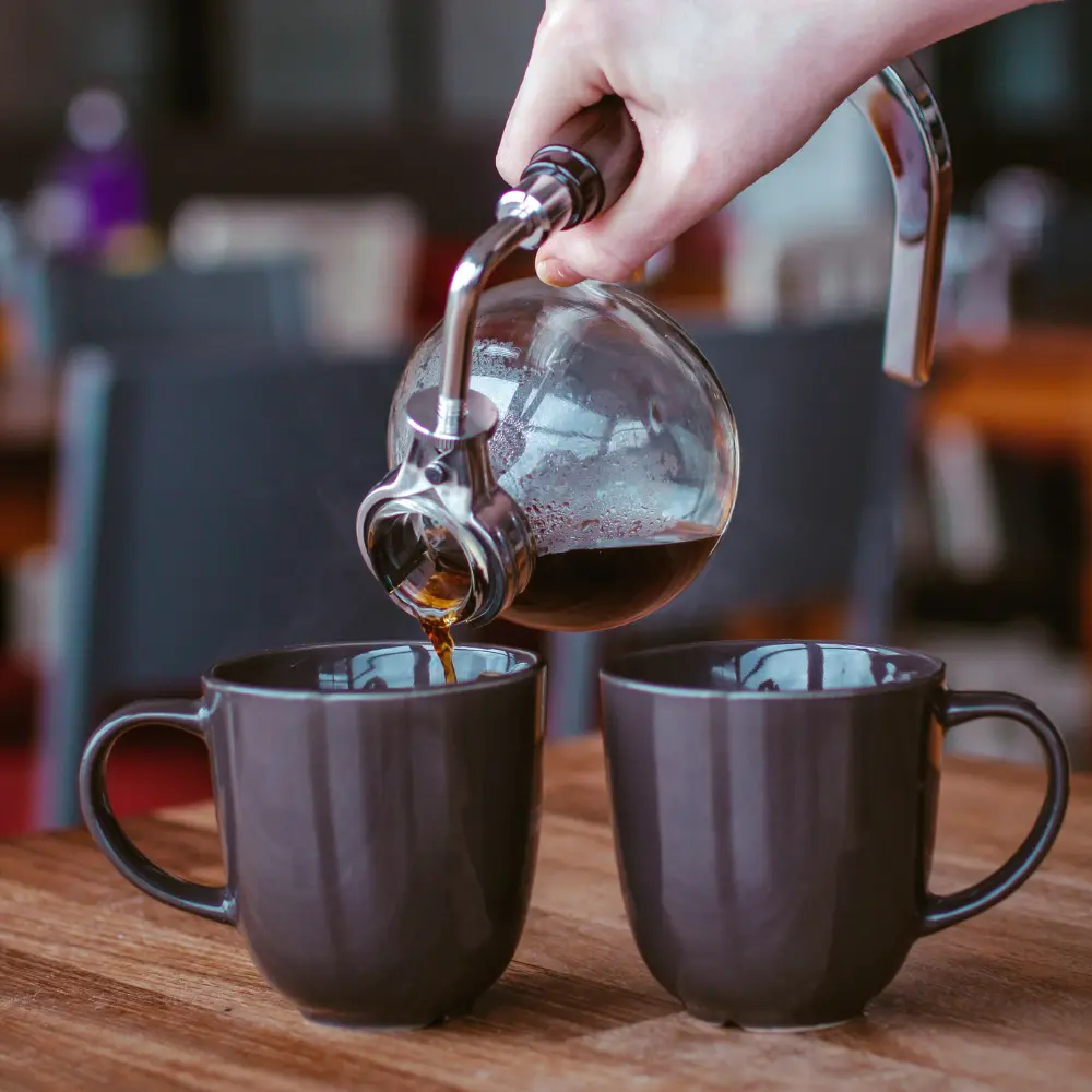 man pouring our vacuum coffee