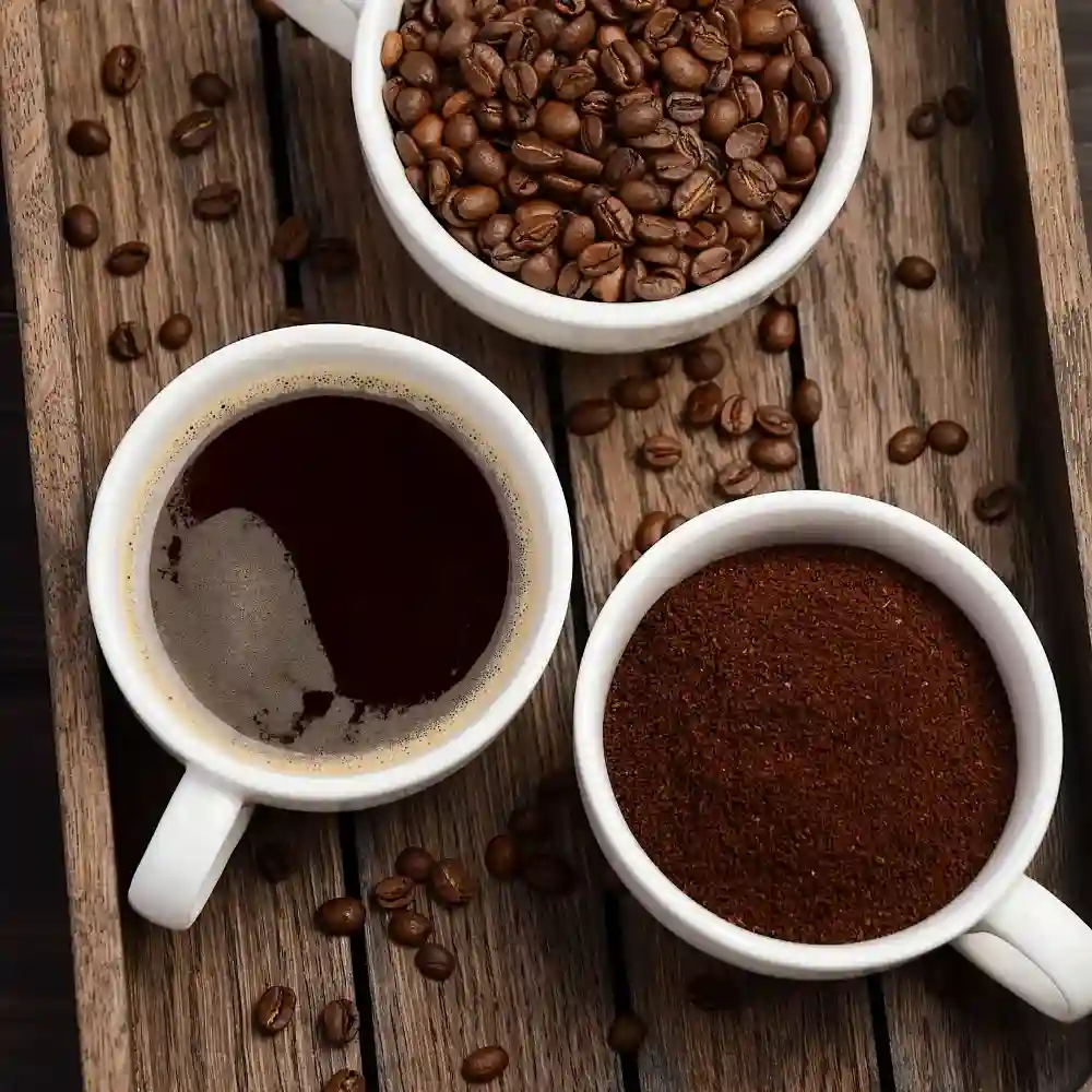 three white mugs with coffee, grounds and beans